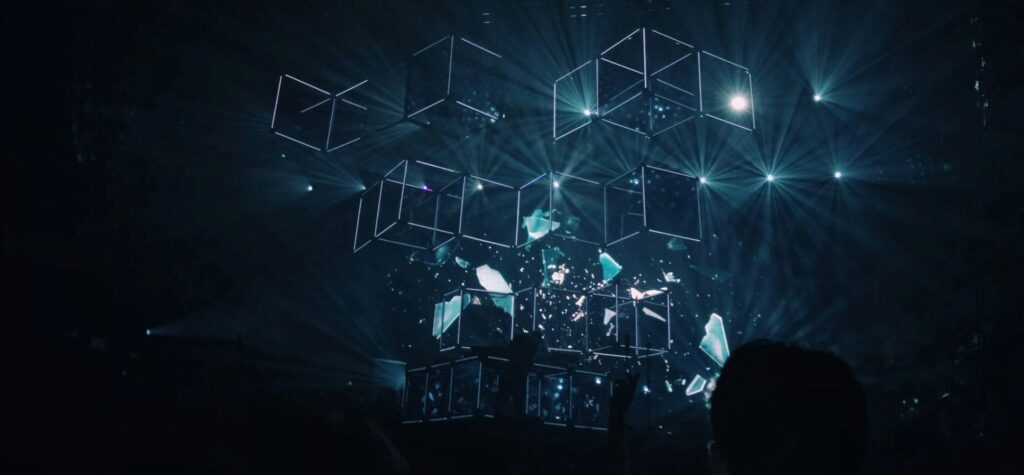 Abstract wireframe cubes and light particles shattering on dark stage