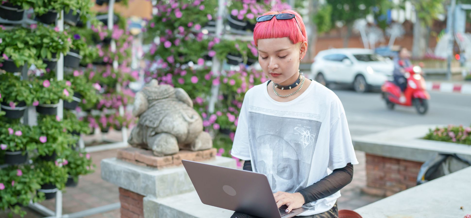 Gen Z professional with pink hair demonstrating the Portfolio Career approach while working remotely on her laptop outdoors.