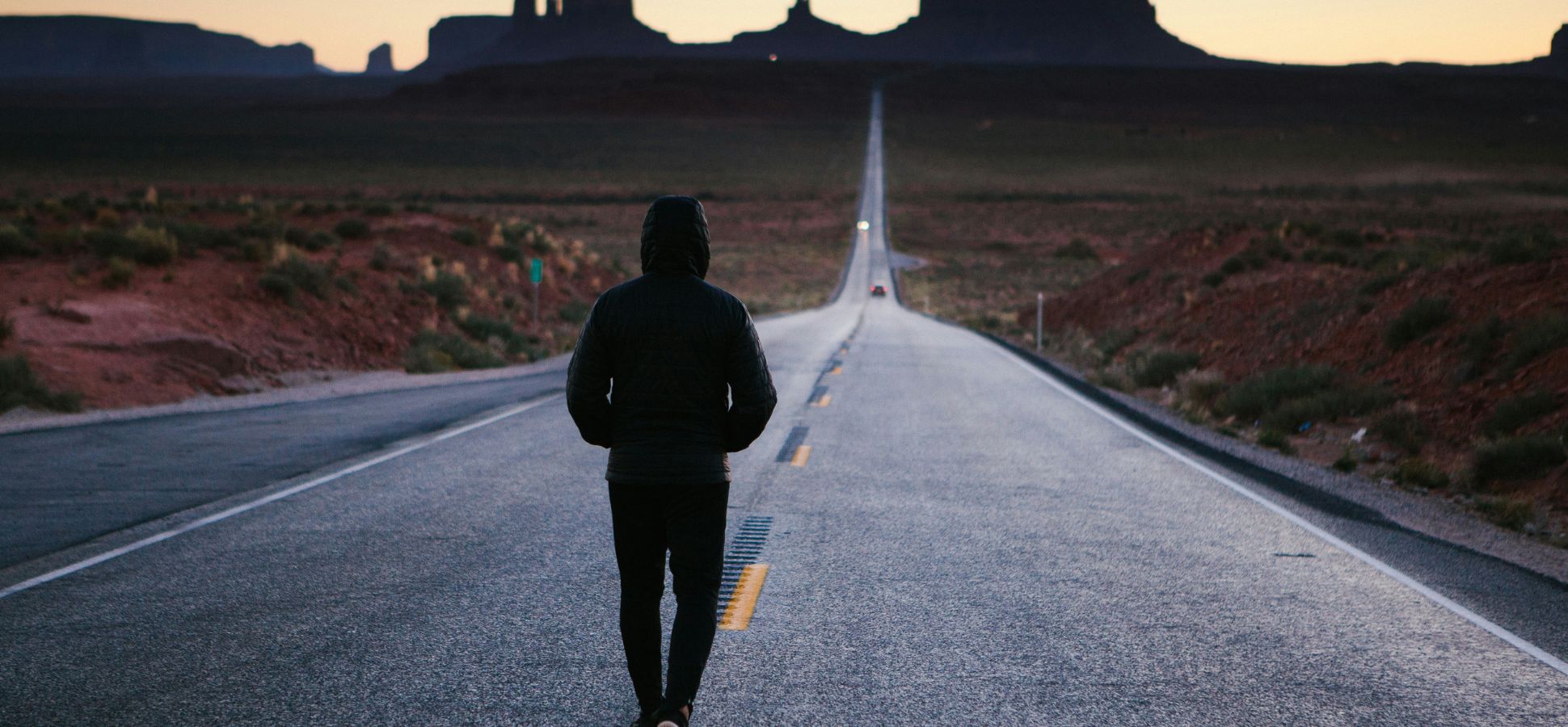 Person walking on desert road toward Monument Valley