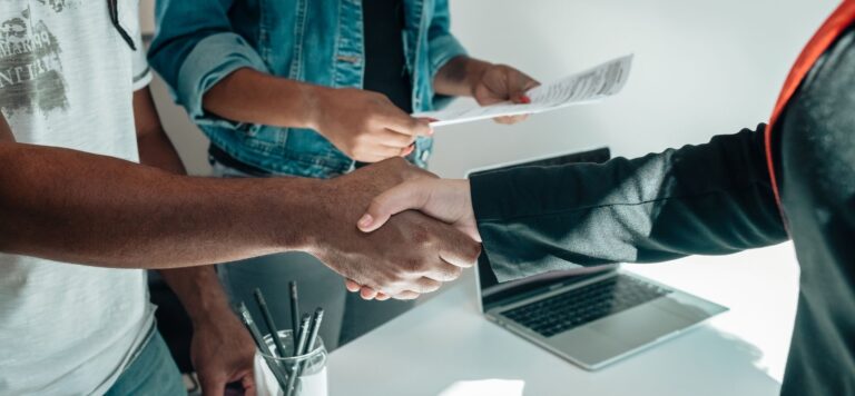 Founders shaking hands over a contract, illustrating how a crisis of trust is resolved by verifiable commitments