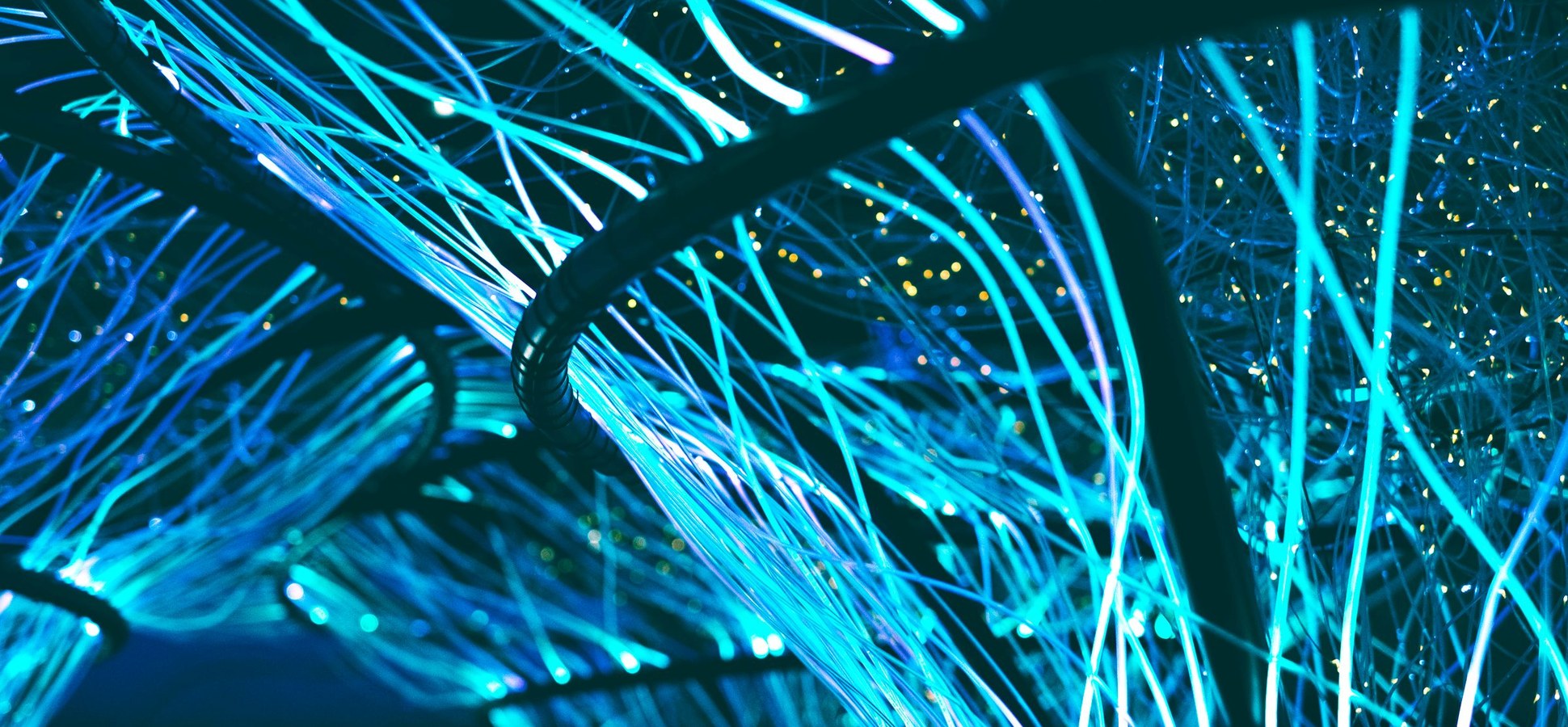 Abstract blue fiber-optic light strands glowing in the dark.
