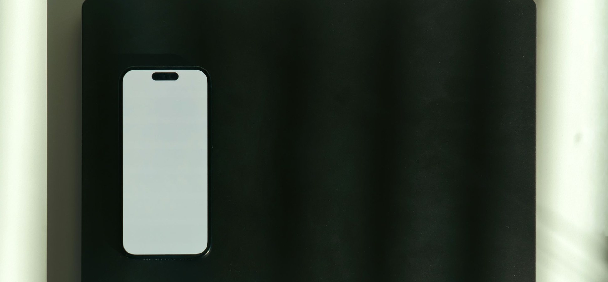 A smartphone with a blank screen on a dark desk.