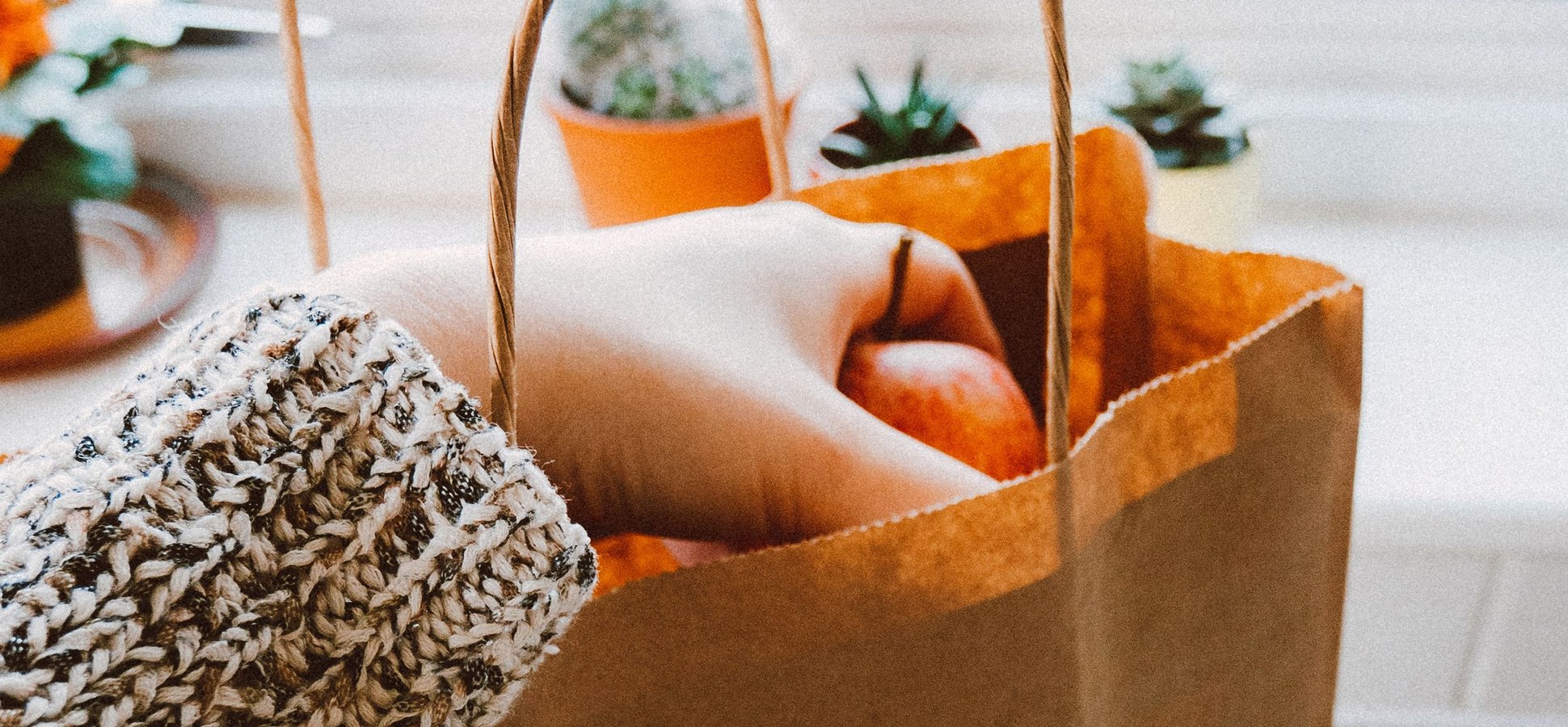 Hand reaching into a brown paper bag of groceries