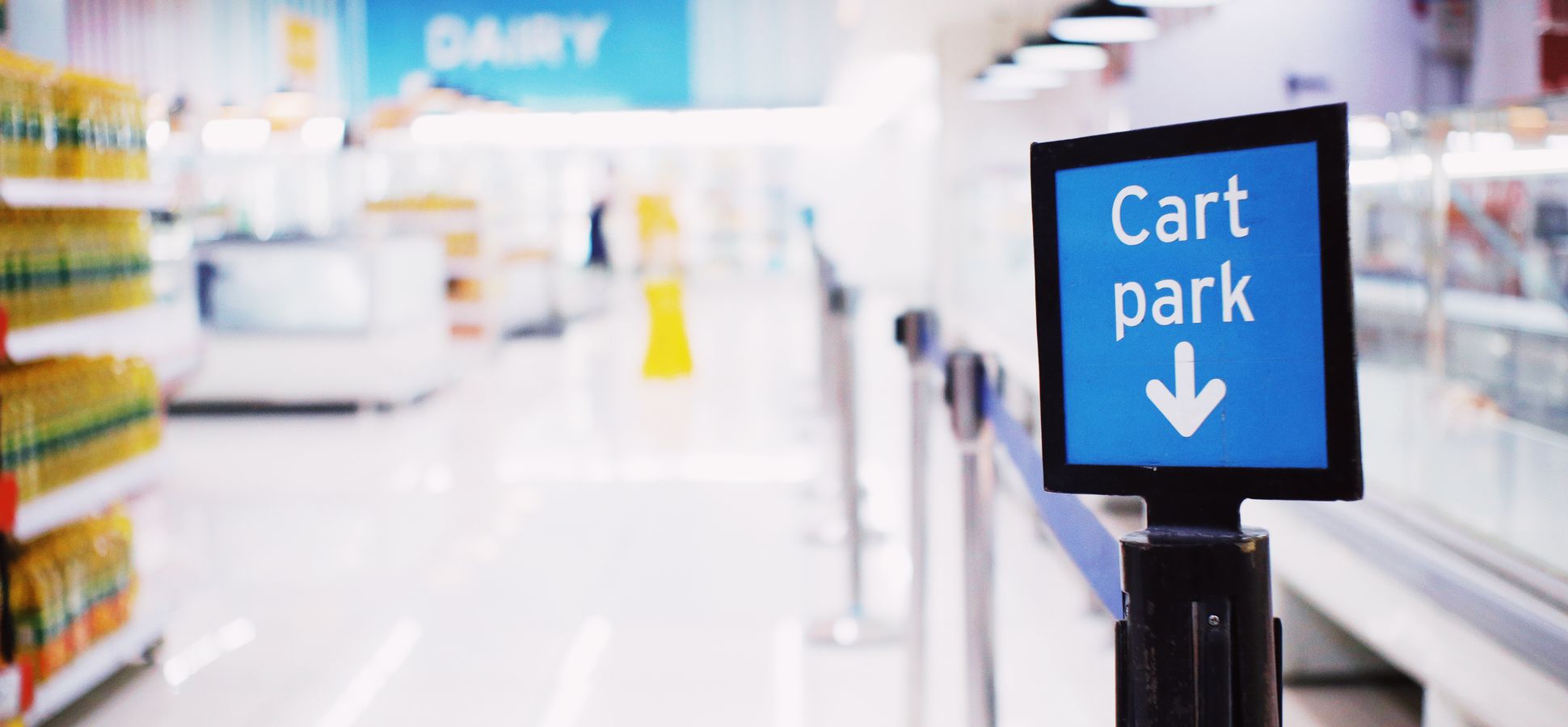 Blurred supermarket aisle with a blue Cart park sign in the foreground