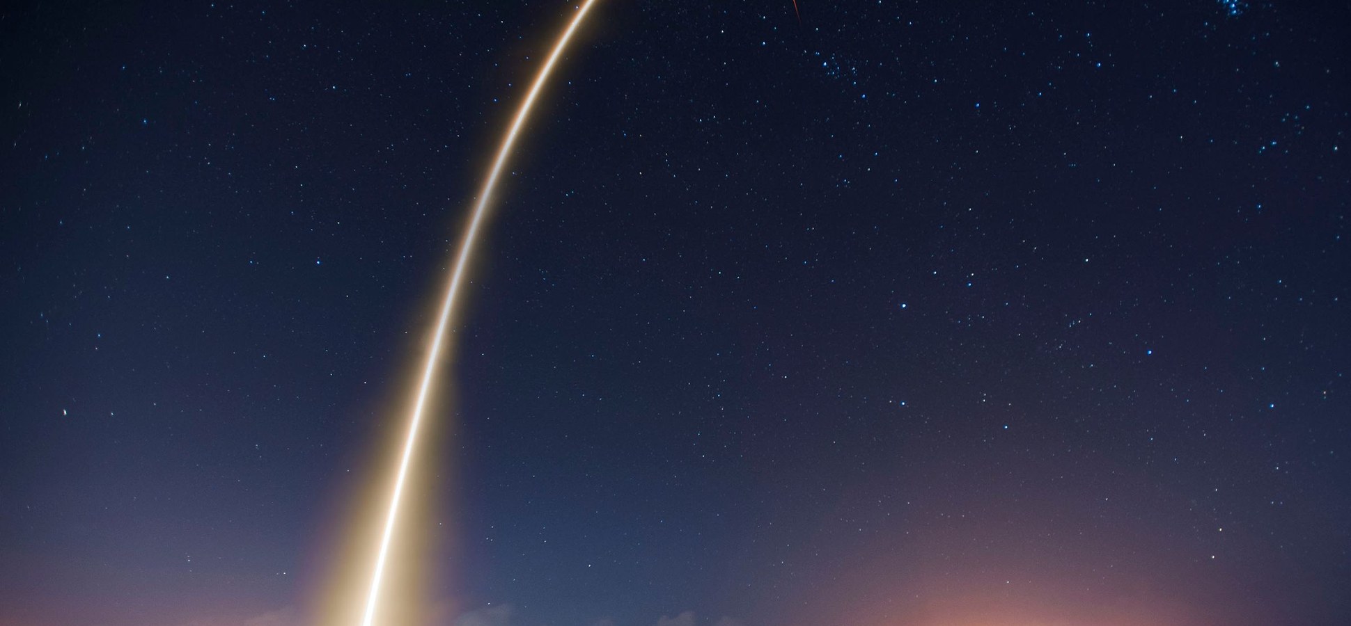 A rocket launch light trail in a starry night sky