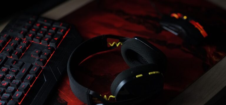 Headphones beside a backlit keyboard on a desk