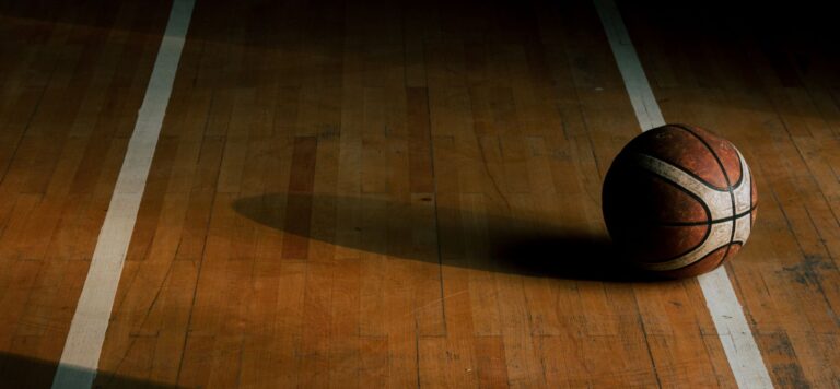 Worn basketball on a wooden gym floor between white court lines
