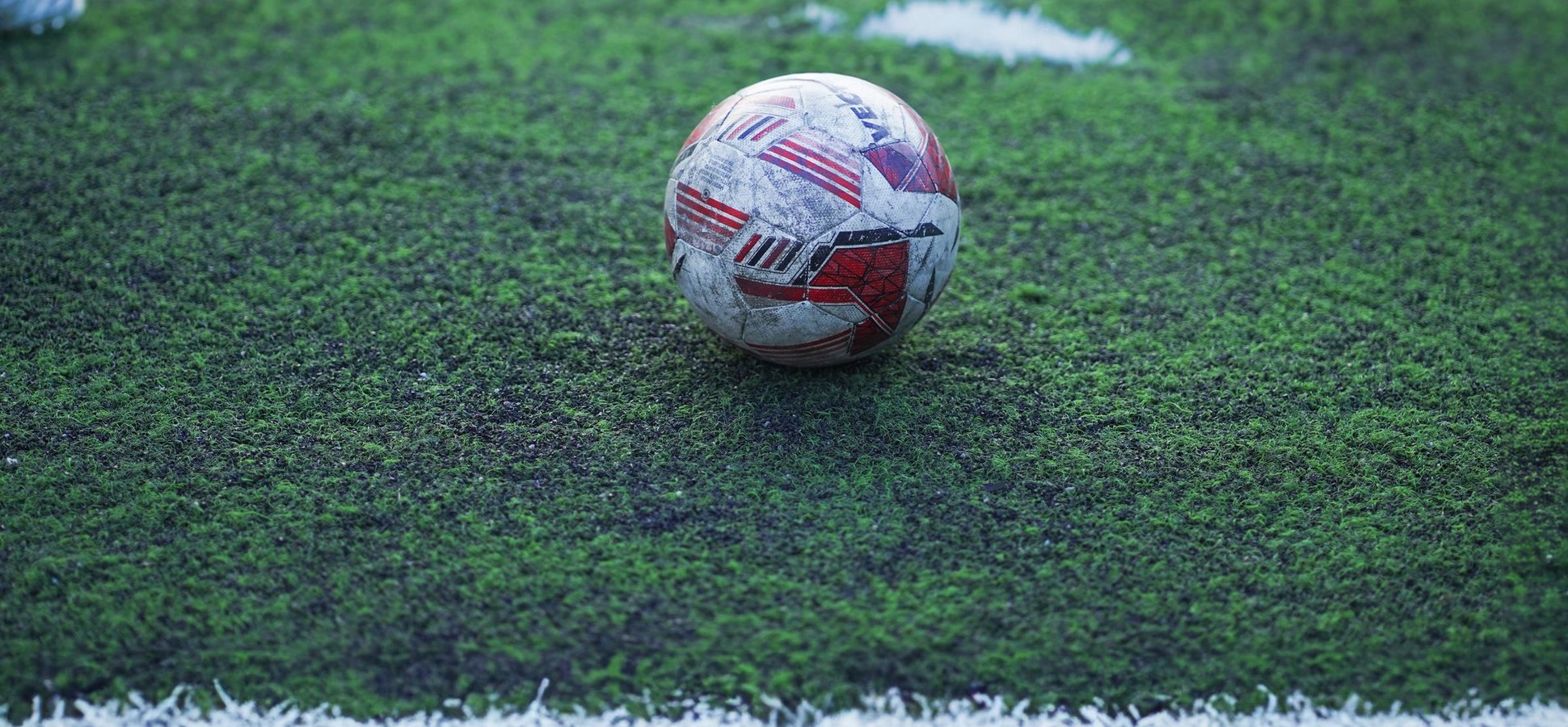 Soccer ball on green artificial turf beside a white line