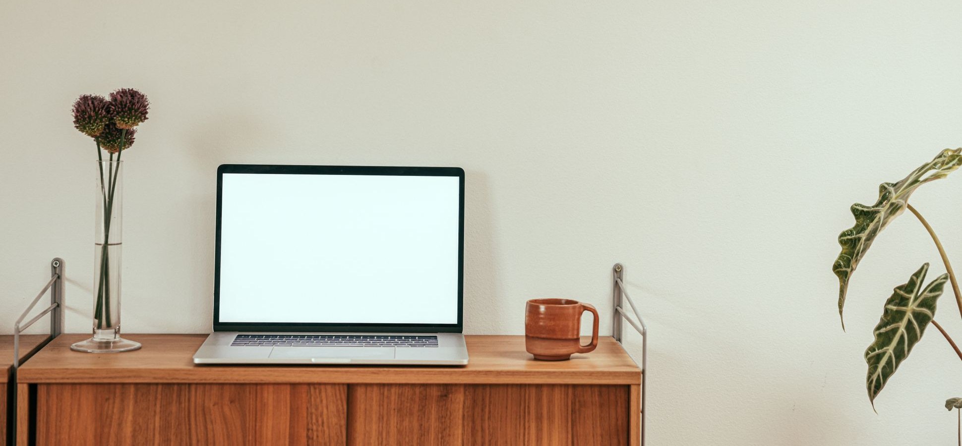 Laptop and a ceramic mug on a wooden sideboard