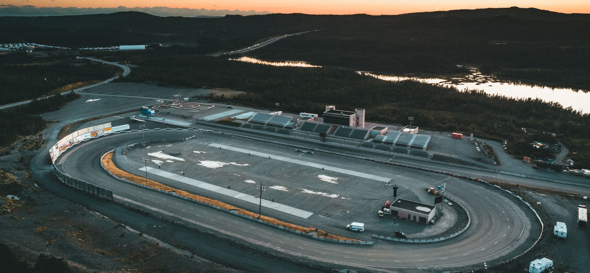 Aerial view of an empty oval racetrack with grandstands at dusk
