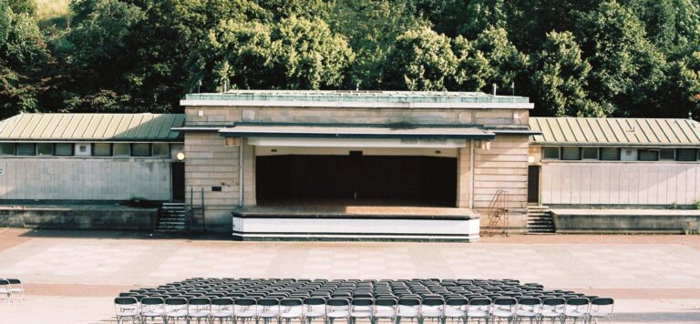 An empty outdoor stage with rows of chairs