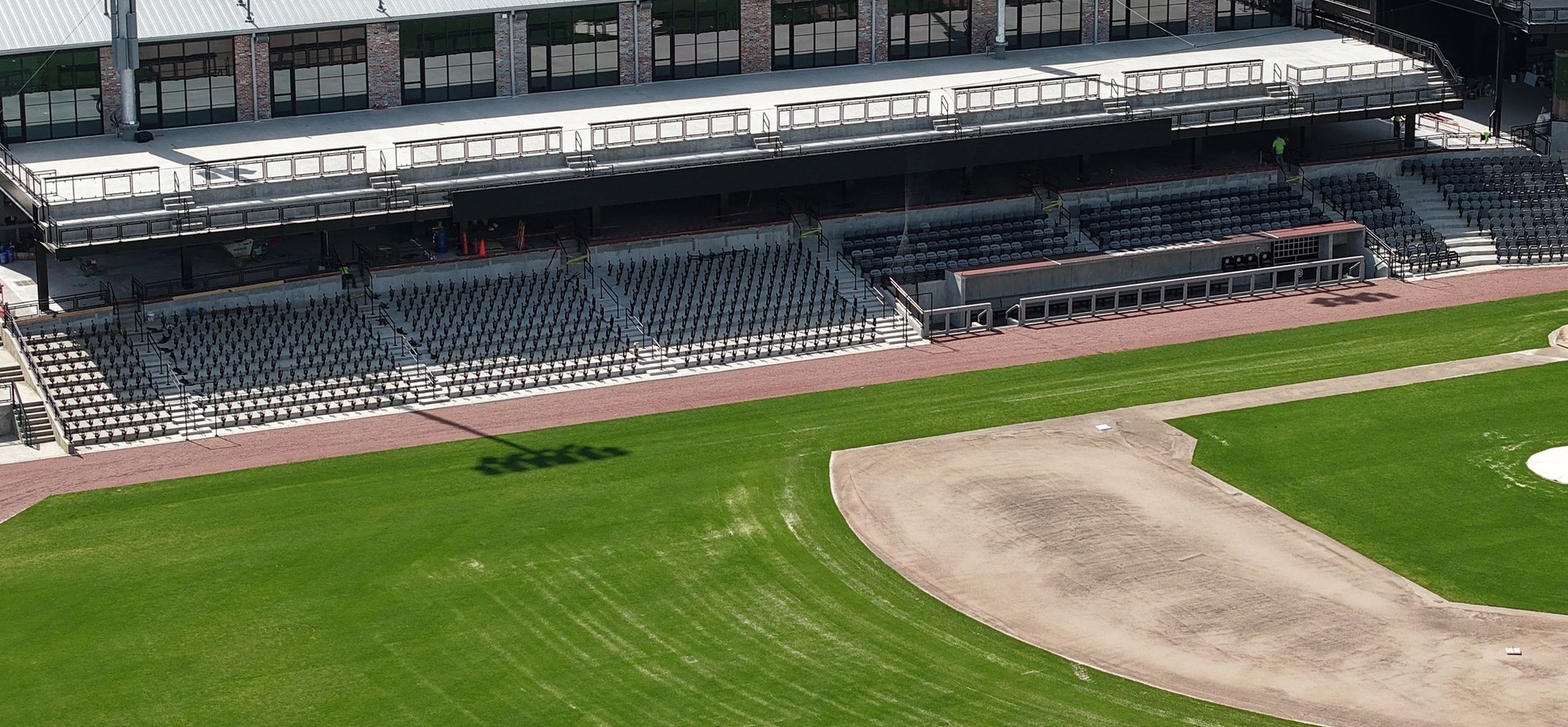 An empty baseball stadium with green field and stands from above.