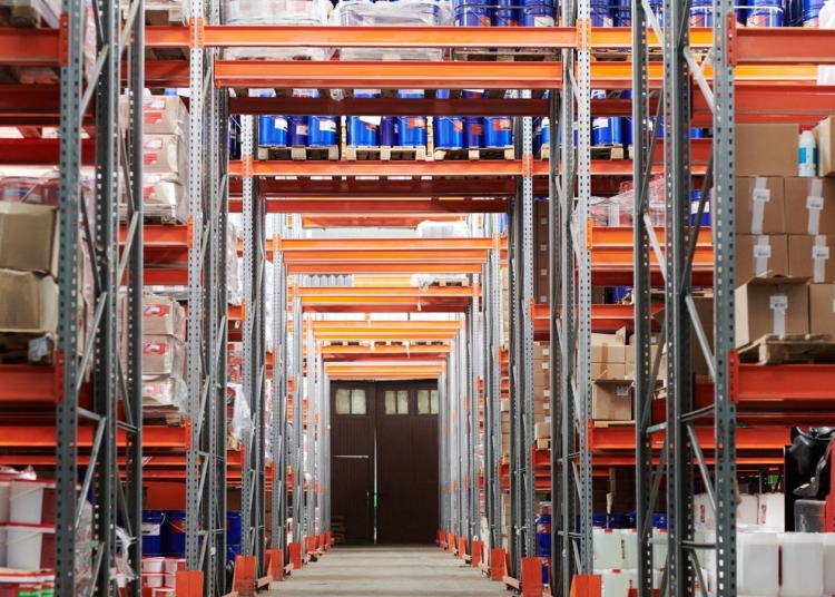Warehouse aisle with orange shelving racks holding boxes and containers