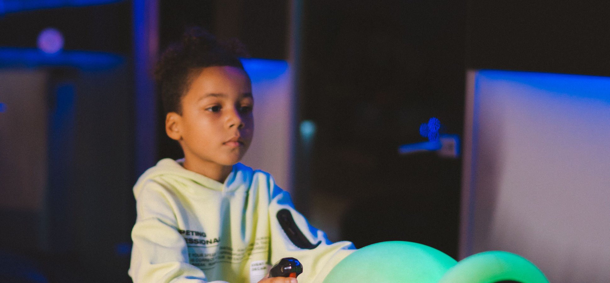 Young player lit by neon arcade screens, the audience behind Steal a Brainrot revenue on Roblox